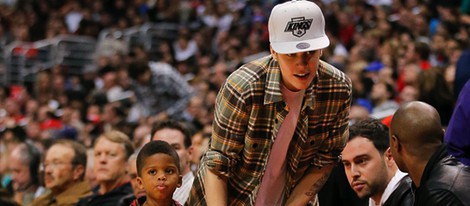 Justin Bieber con un niño de la mano en la NBA