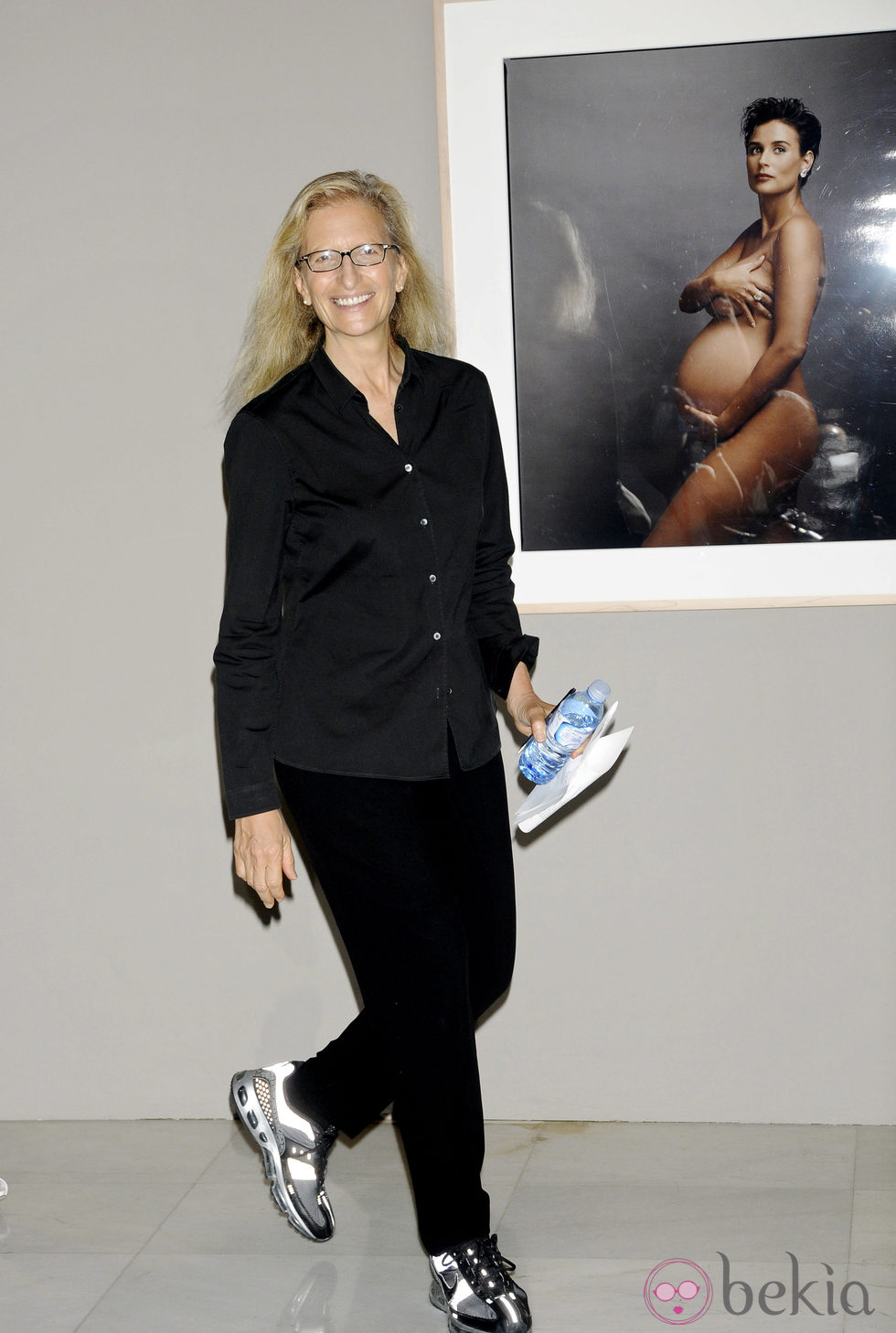 Annie Leibovitz posando con su fotografía de Demi Moore desnuda embarazada