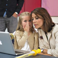 Una niña habla al oído a Marie de Dinamarca en su visita al Hospital de Odense