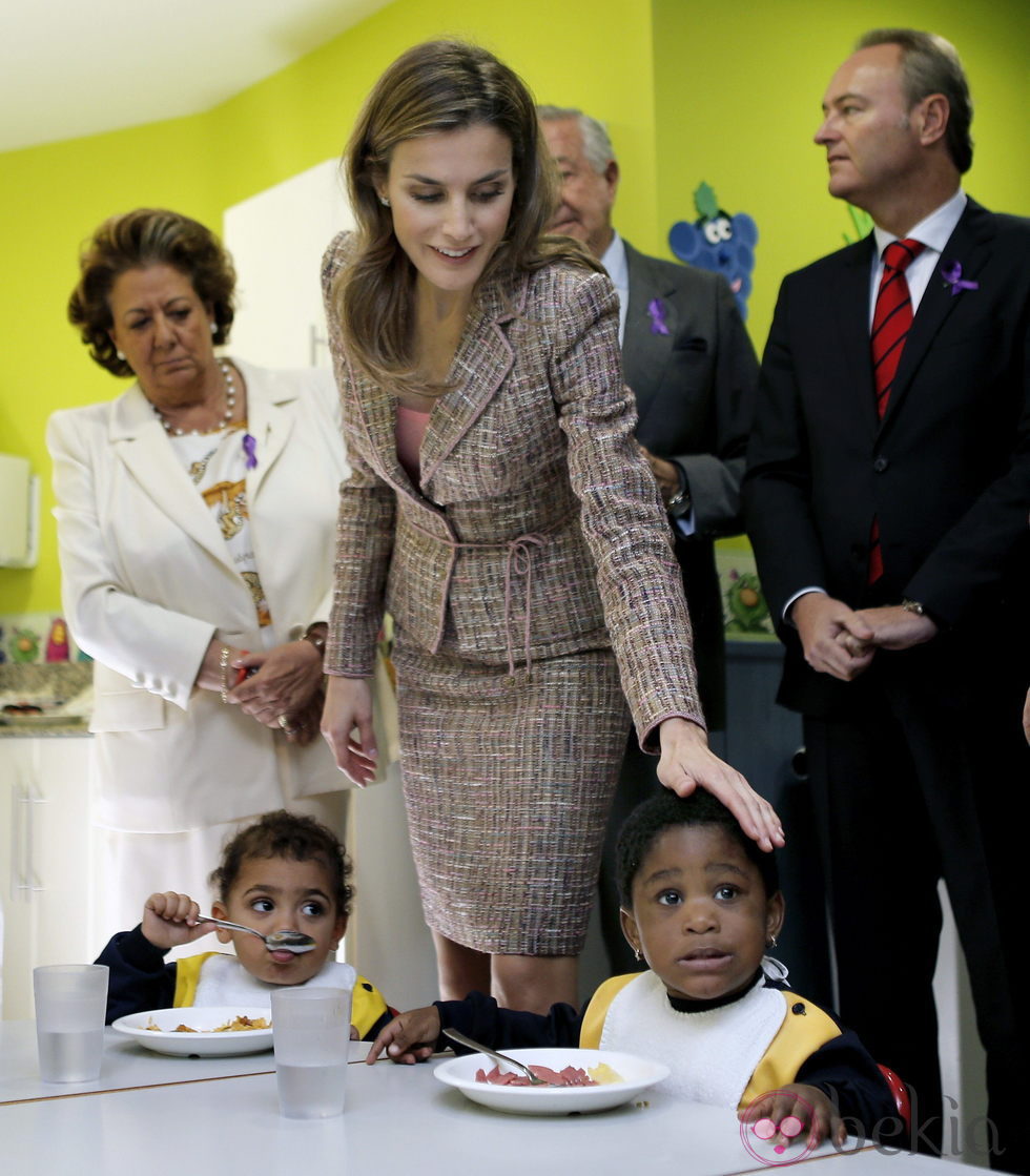 La Princesa Letizia acaricia a una niña en la Asociación Valenciana de Caridad