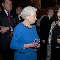 La Reina Isabel charla con Joan Collins en una recepción en Buckingham Palace