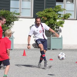 Haakon de Noruega jugando al fútbol en un partido amistoso