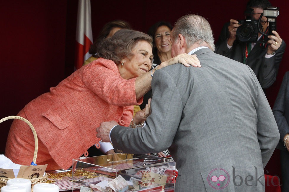 La Reina Sofía da un beso al Rey Juan Carlos en el Día de la Banderita 2014