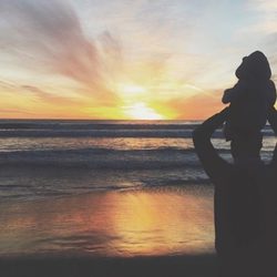 Pedro Castro viendo una puesta de sol con su hijo Leo en la playa