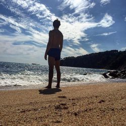 Andrés Velencoso en bañador mirando al mar desde una playa