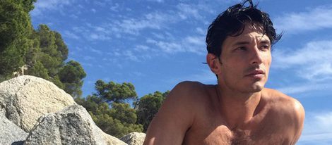 Andrés Velencoso con el torso desnudo sobre una roca