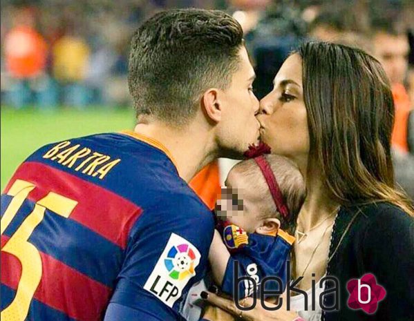 Marc Bartra y Melissa Jiménez se dan un beso junto a su hija Gala en el Camp Nou