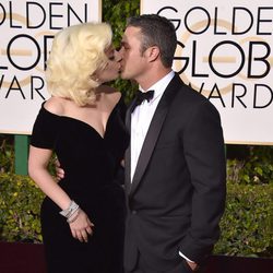 Lady Gaga y Taylor Kinney besándose en la alfombra roja de los Globos de Oro 2016