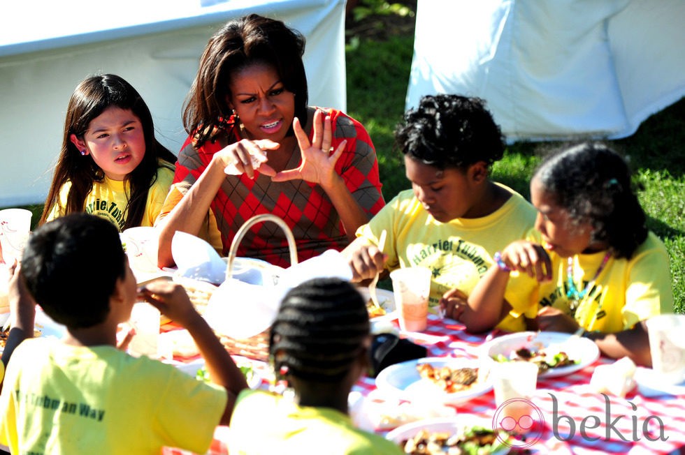 Michelle Obama charla mientra come con unos niños tras recoger la cosecha en la Casa Blanca