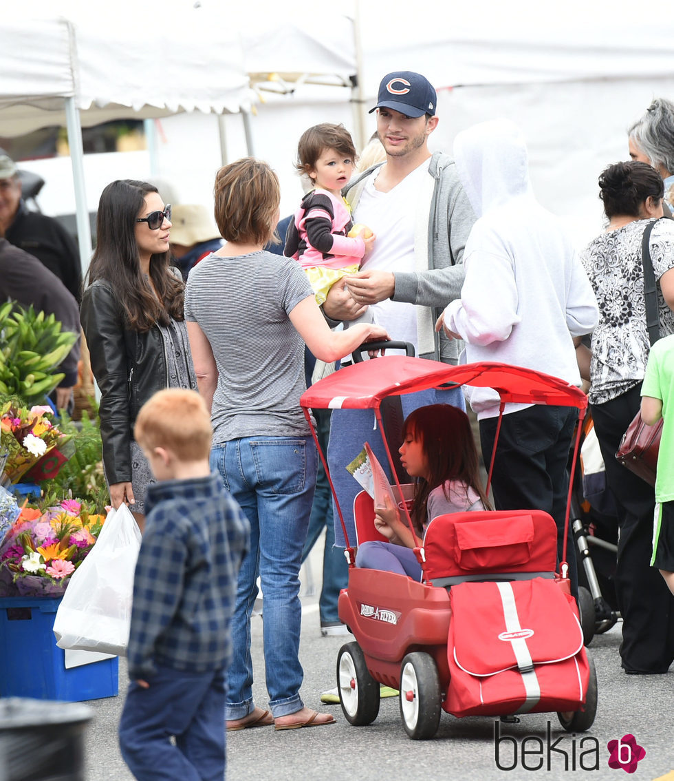 Mila Kunis, Ashton Kutcher y su hija Wyatt charlando con unos conocidos