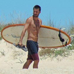 Hugo Silva con el torso desnudo y una tabla de surf